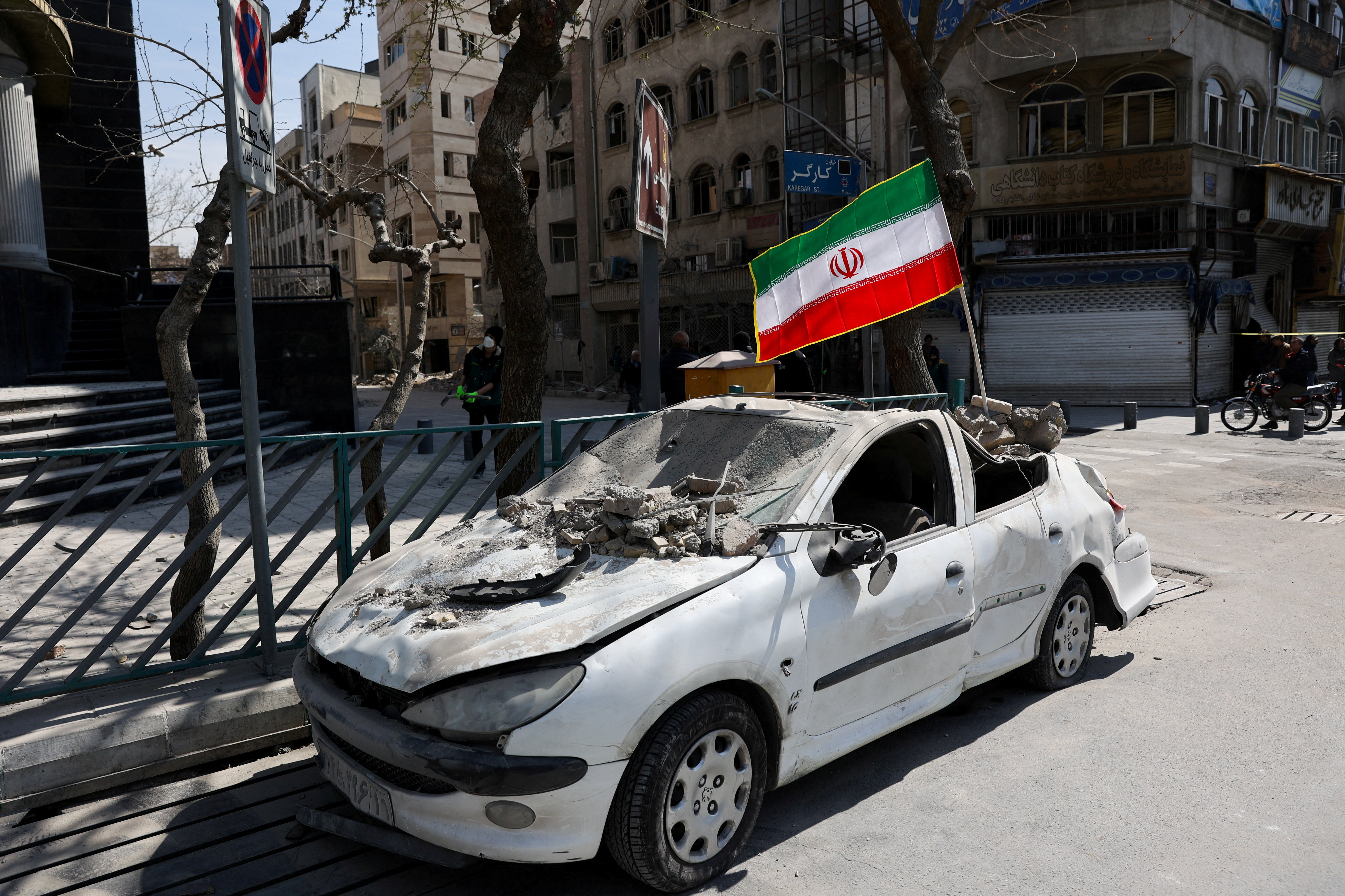 Iranian flag on damaged car — symbol of civilian impact, Mar 4
